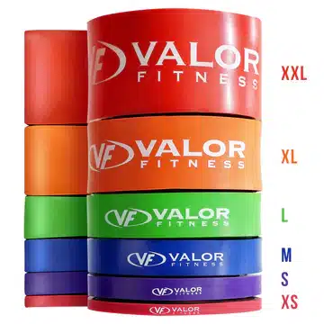 Stacked Valor Fitness weight plates in red, orange, green, blue, and purple with size labels XXL to XS on the side, logo visible beneath each plate.